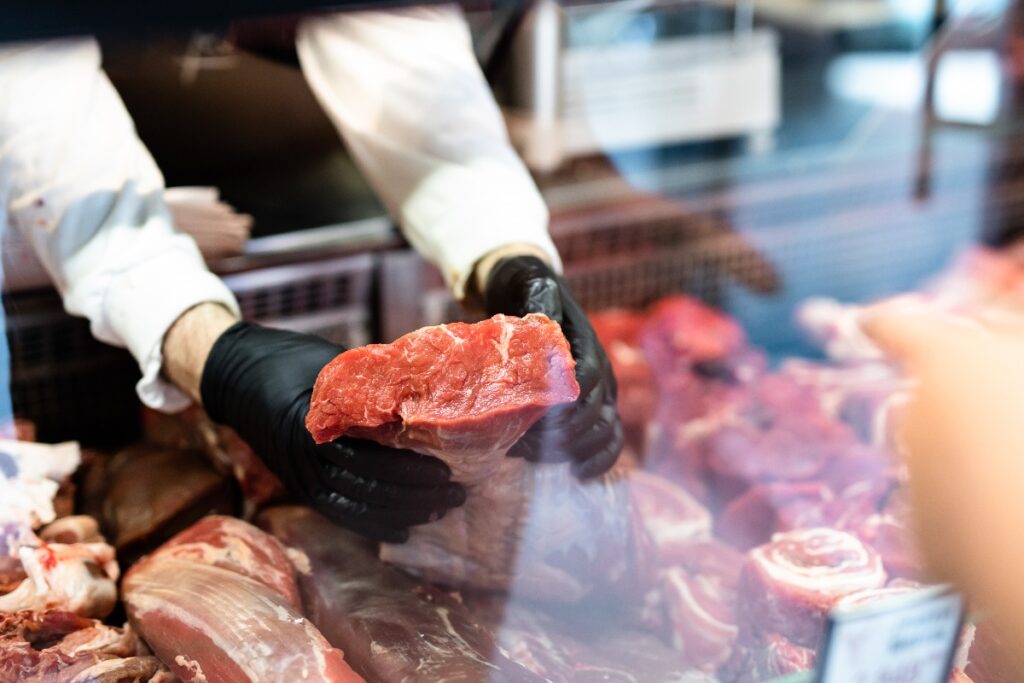 Closeup on butchers hands in gloves working in butchery jpg